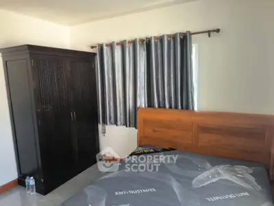 Cozy bedroom with wooden bed and wardrobe, featuring elegant curtains and natural light.