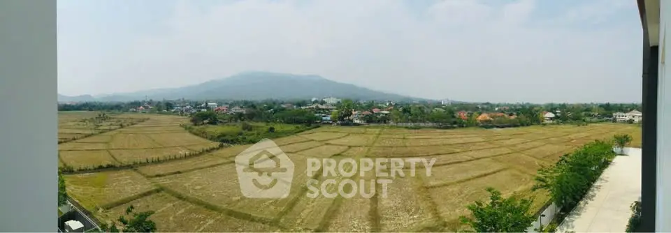 Stunning panoramic view of expansive fields and distant mountains from a high vantage point, perfect for serene living.