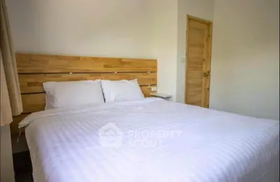 Cozy bedroom with wooden accents and white linens, perfect for relaxation.