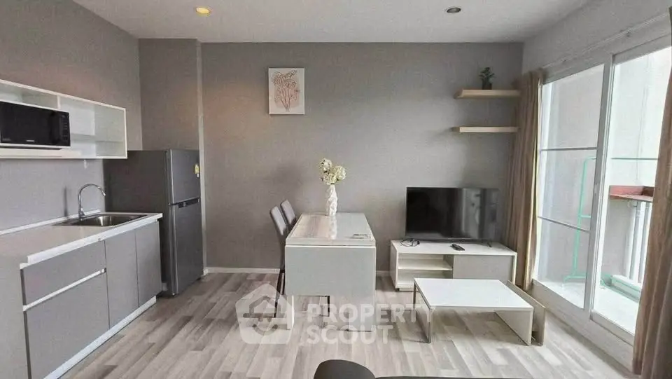 Modern open-layout living room with kitchen, featuring sleek furniture and natural light.