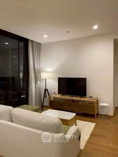 Modern living room with cozy sofa, sleek TV stand, and ambient lighting in a stylish apartment.