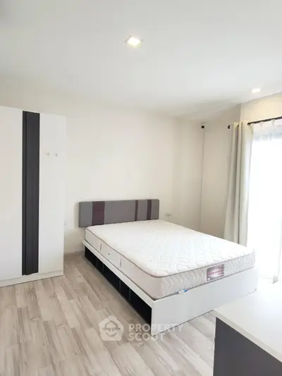 Modern minimalist bedroom with natural light and sleek furnishings.