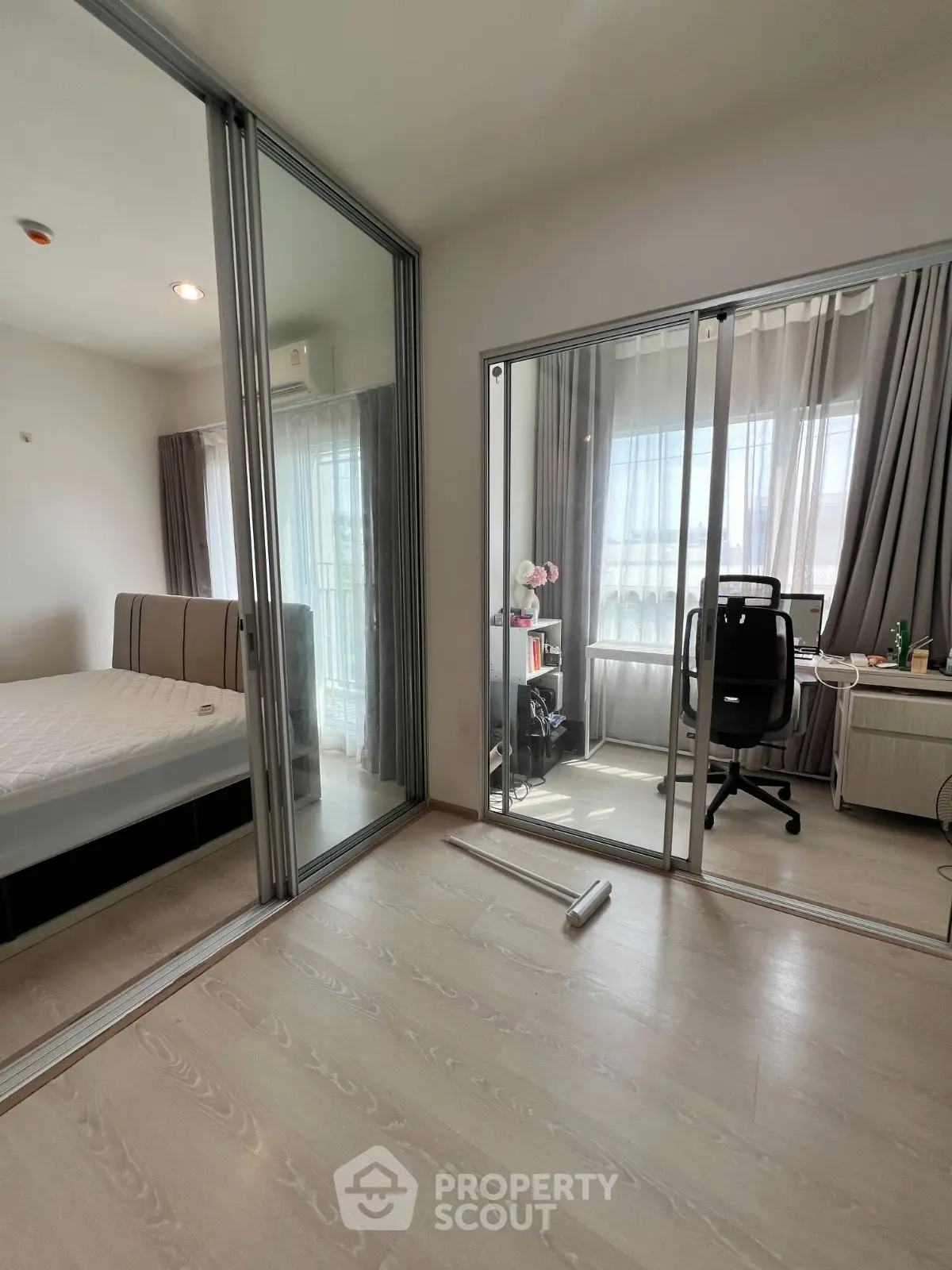 Modern bedroom with glass sliding doors and study area, featuring natural light and sleek furnishings.