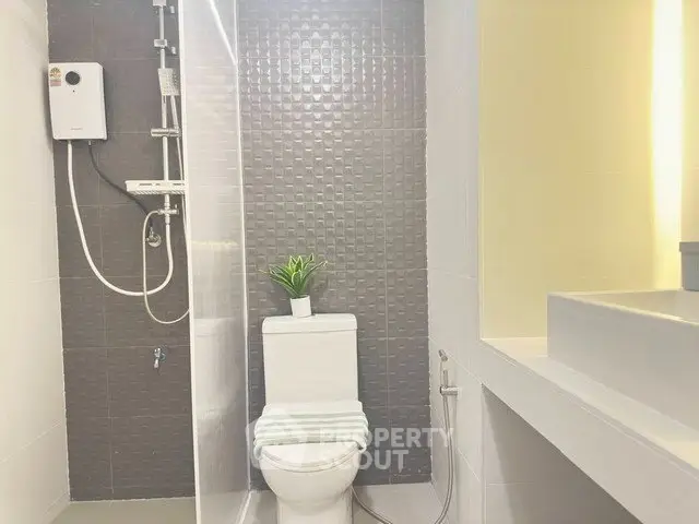 Modern bathroom with sleek design and stylish fixtures, featuring a shower and toilet.