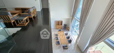 Stunning modern duplex with high ceilings and elegant dining area, featuring floor-to-ceiling windows and stylish furniture.