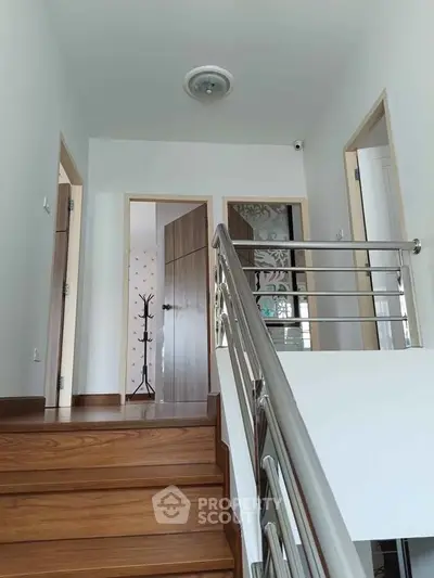 Modern interior staircase with wooden steps and sleek metal railing in a contemporary home.