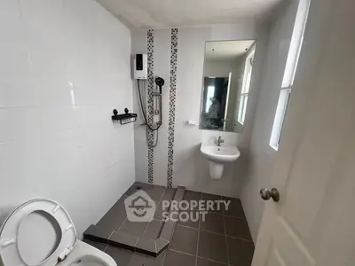 Modern bathroom with shower, toilet, and sink in a sleek tiled design.