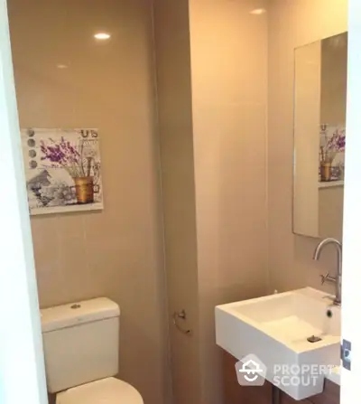 Modern bathroom with sleek sink and wall art in contemporary apartment.