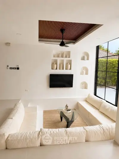 Luxurious sunken living room with modern decor and large windows offering garden views.