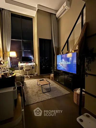 Modern living room with high ceilings, large windows, and stylish decor at night.
