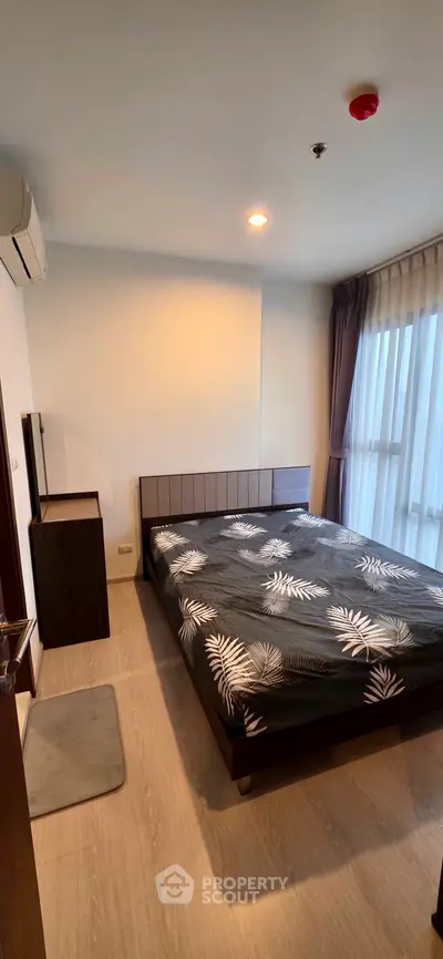 Modern bedroom with stylish decor and large window for natural light.