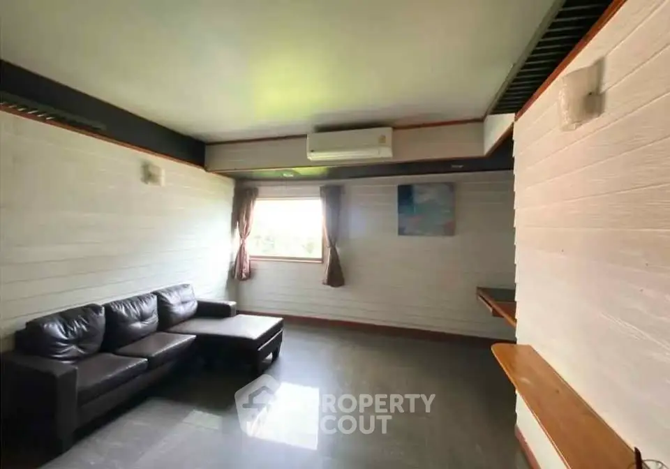 Spacious living room with modern sofa and large window for natural light.