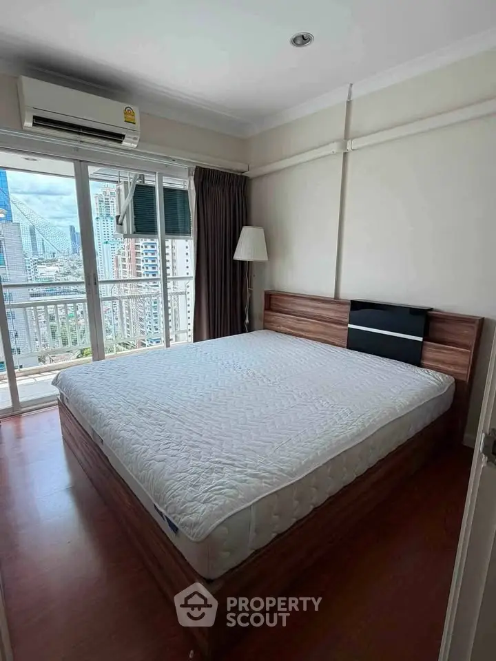 Spacious bedroom with city view and large window in modern apartment