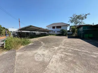 Spacious outdoor area with concrete pavement and covered parking, ideal for versatile use.