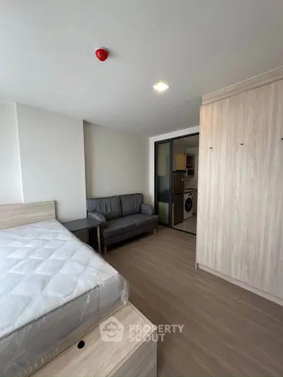 Modern studio apartment with cozy living area and compact kitchen featuring a washing machine.