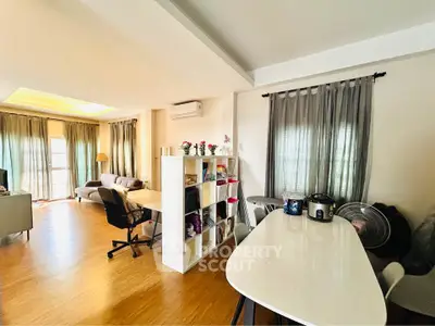 Spacious living room with modern decor and natural light, featuring a cozy seating area and dining space.