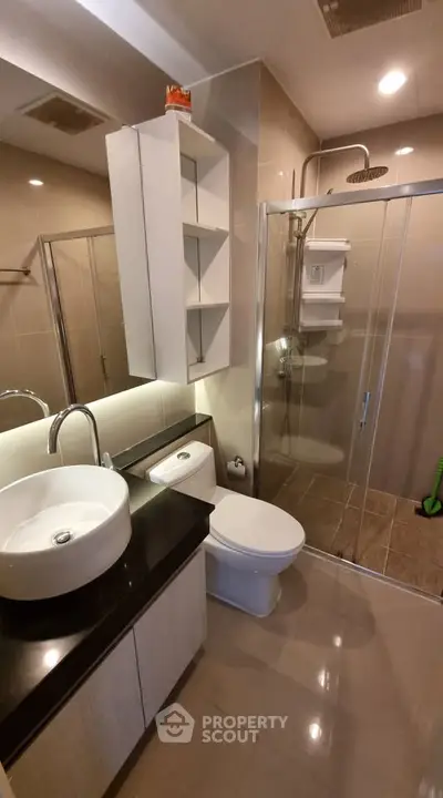 Modern bathroom with glass shower and sleek vanity in contemporary apartment.