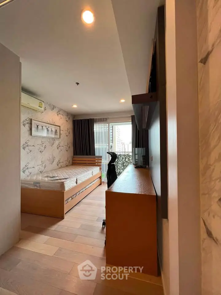 Modern bedroom with stylish decor and large window offering city views, featuring a cozy bed and sleek furniture.