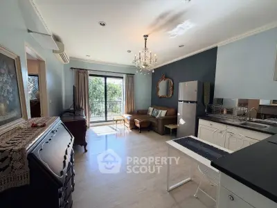 Charming living room with elegant chandelier and open kitchen layout, featuring a cozy seating area and natural light.