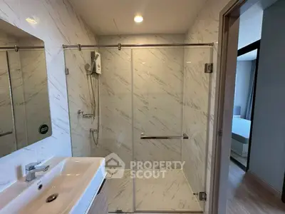 Modern bathroom with glass shower enclosure and sleek sink in a stylish apartment.