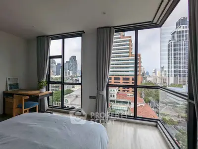 Spacious bedroom with stunning city view through large windows in modern high-rise apartment.
