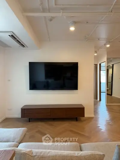 Modern living room with wall-mounted TV and stylish wooden flooring