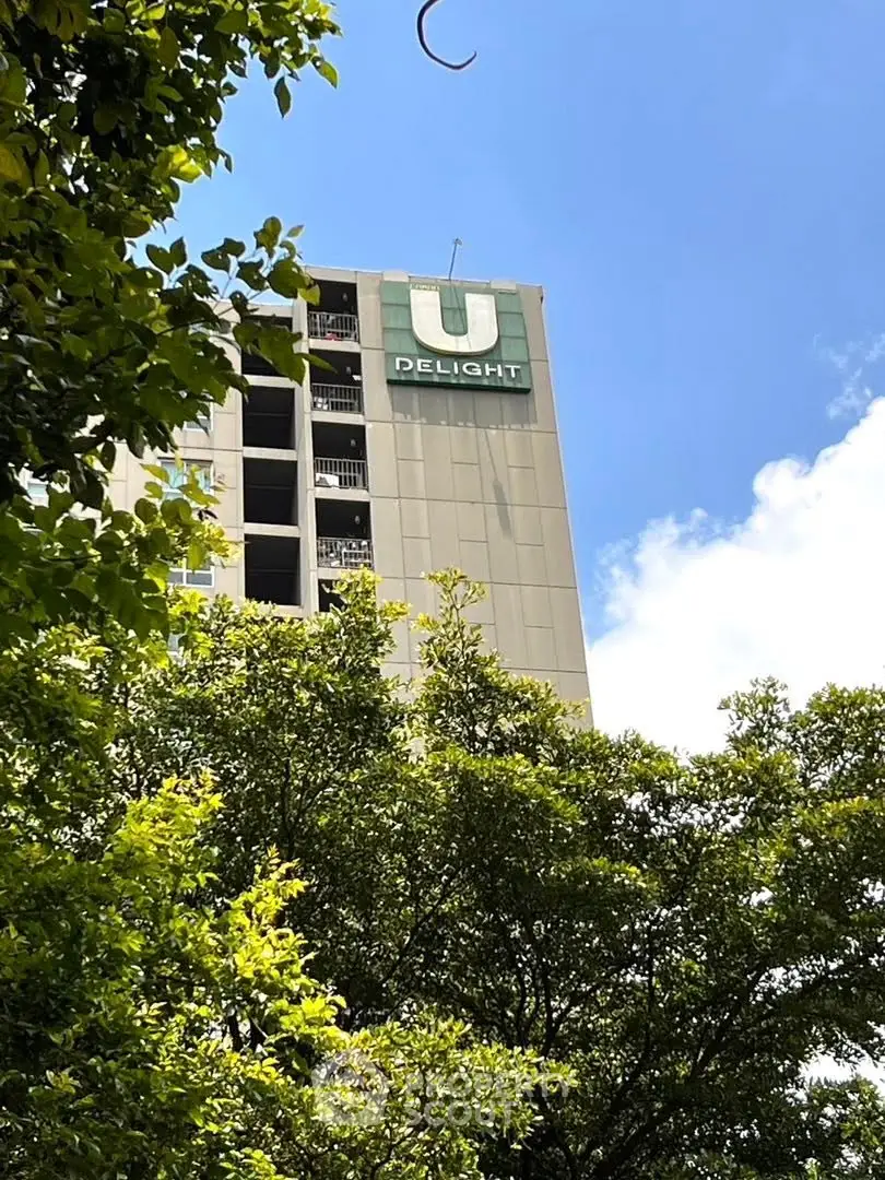 Modern high-rise building with lush greenery and clear blue sky.