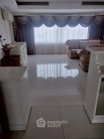 Spacious living room with elegant drapes and wicker furniture, perfect for relaxation.