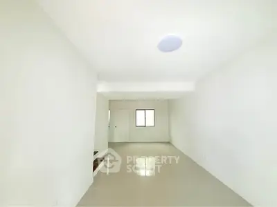 Spacious minimalist living room with white walls and tiled flooring