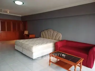 Spacious bedroom with elegant bed and cozy seating area in modern apartment.