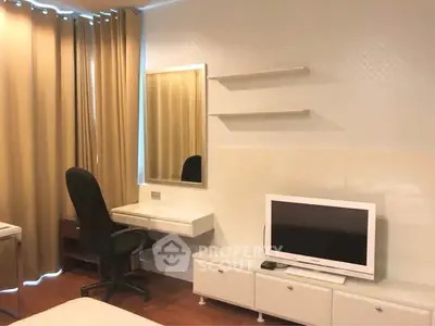 Modern bedroom with TV, desk, and mirror, featuring elegant curtains and sleek furniture.