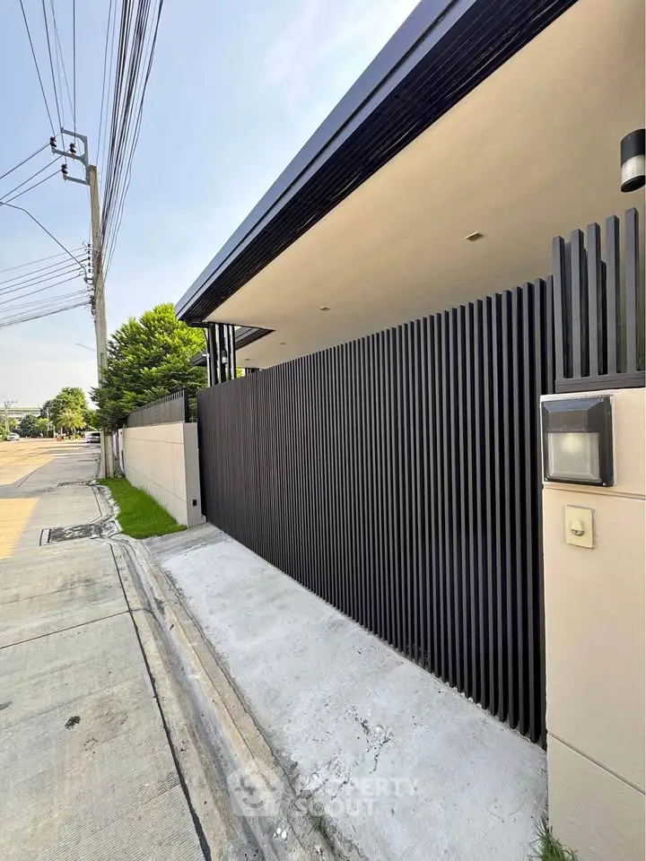 Modern exterior entrance with sleek black gate and minimalist design.