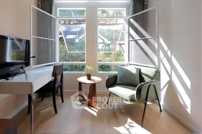 Bright living room with modern furniture and large windows offering garden views.