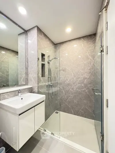 Modern bathroom with glass shower and sleek vanity in contemporary apartment.