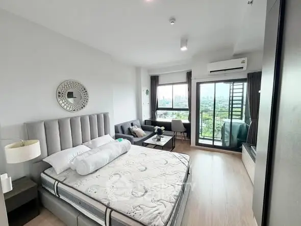 Spacious bedroom with modern decor and balcony offering stunning city views.