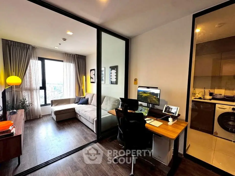 Modern living room with study area and glass partition, featuring stylish decor and natural light.