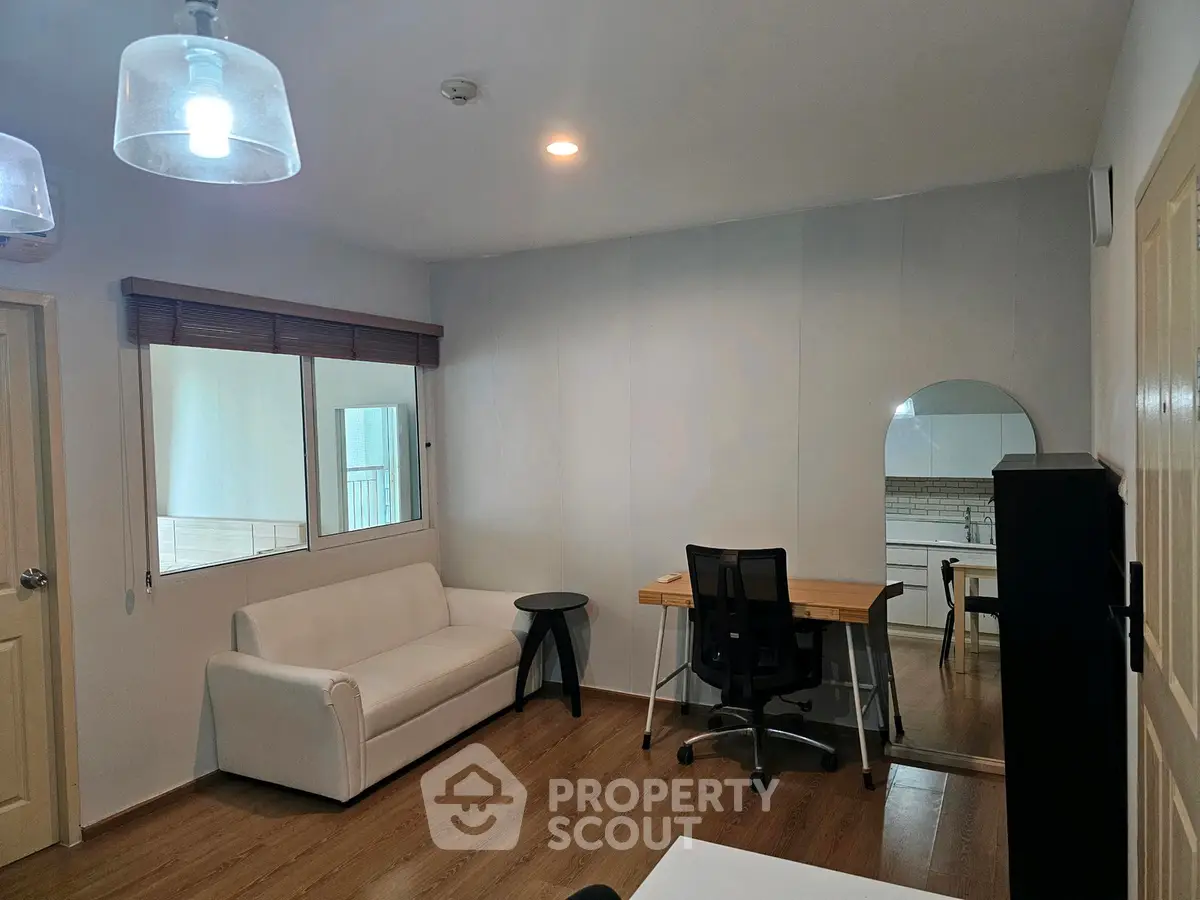 Modern study room with desk, chair, and sofa in a cozy apartment setting.