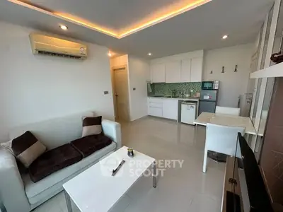 Modern living room with open kitchen, sleek furniture, and ambient lighting.