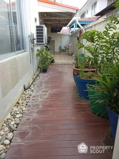 Charming garden pathway with wooden deck and lush potted plants in a cozy residential setting.