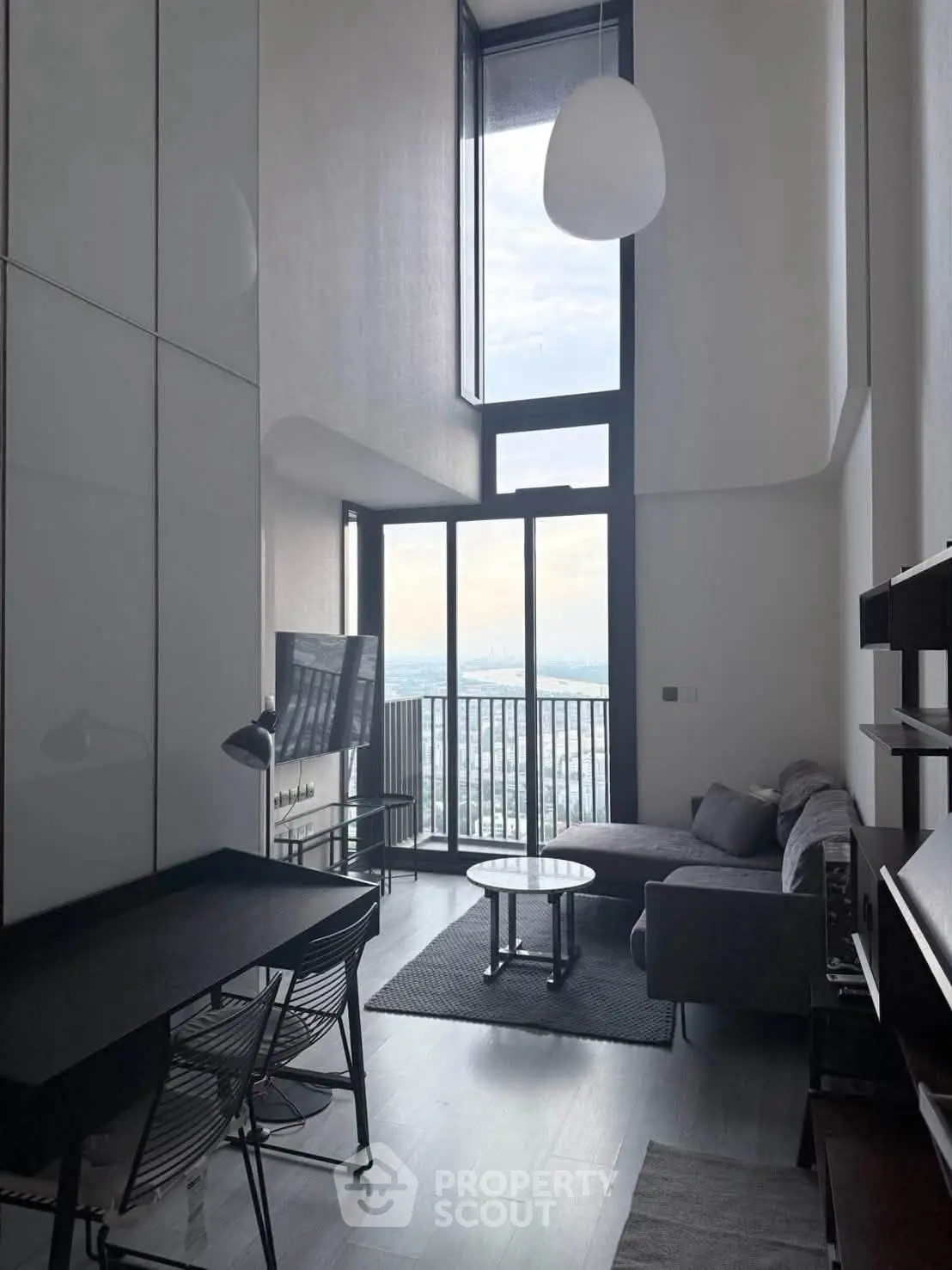 Modern living room with high ceilings and stunning city view from large windows.