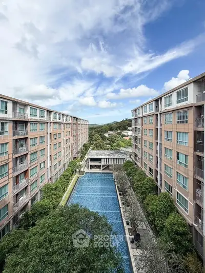 Stunning aerial view of modern apartment complex with central pool and lush greenery.