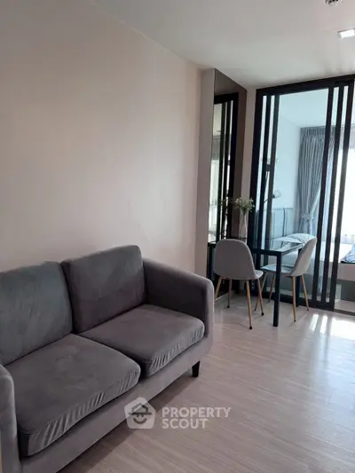 Modern living room with sleek furniture and glass partition leading to bedroom