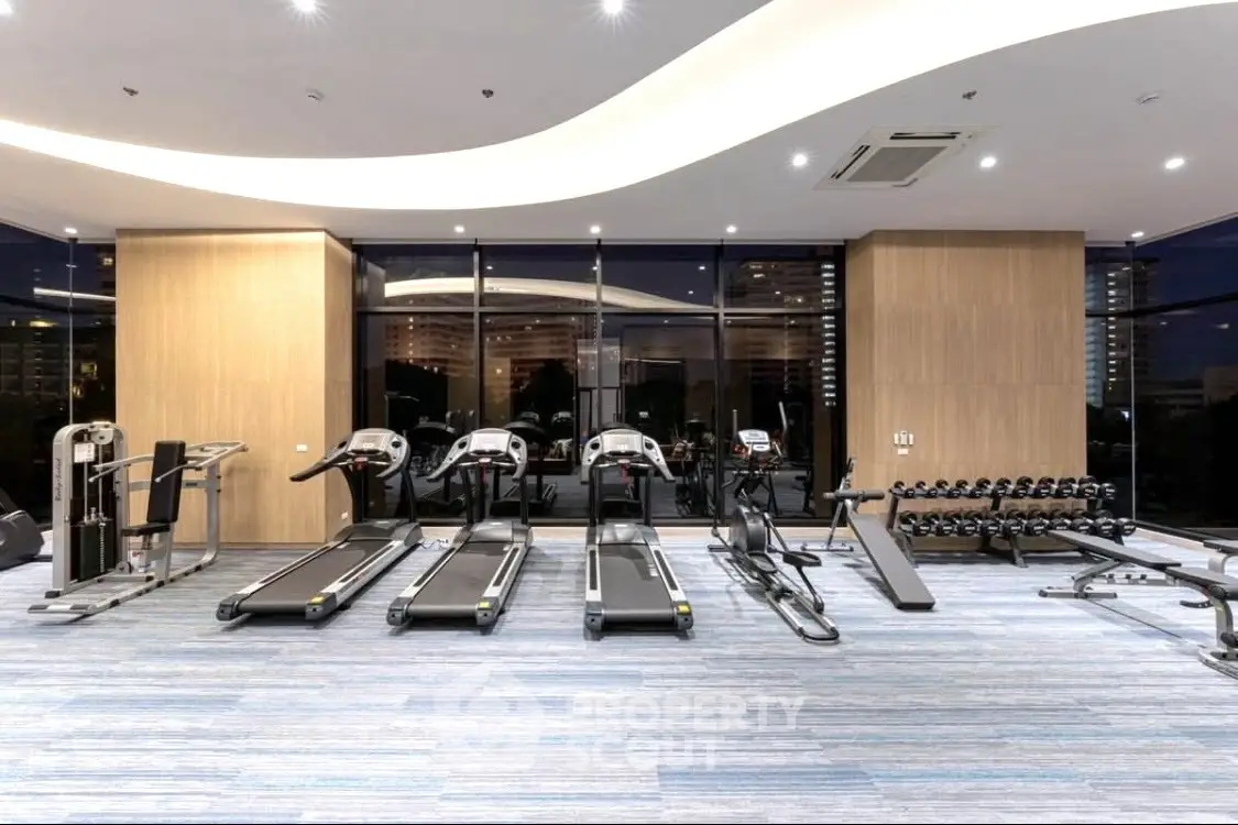 Modern gym with treadmills and weights in luxury apartment building