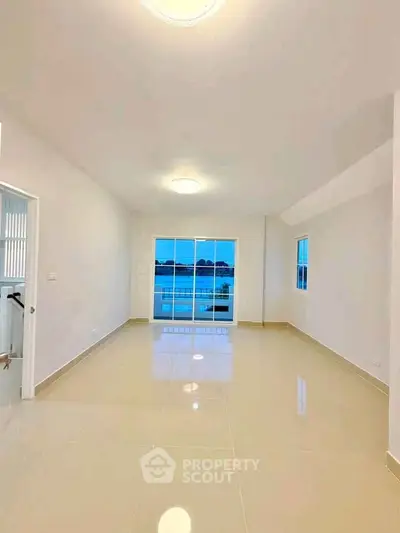 Spacious living room with glossy tiled floors and large windows offering a serene view.