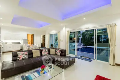 Luxurious living room with modern decor and pool view, featuring a spacious leather sofa and elegant lighting.