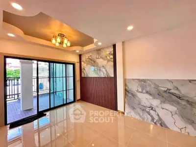 Elegant living room with marble accents and modern lighting, featuring large sliding glass doors opening to a patio.