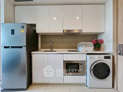 Modern compact kitchen with appliances including fridge, microwave, and washing machine.
