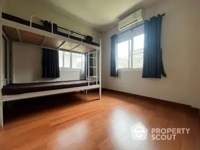 Spacious bedroom with bunk bed and air conditioning, featuring wooden flooring and natural light.