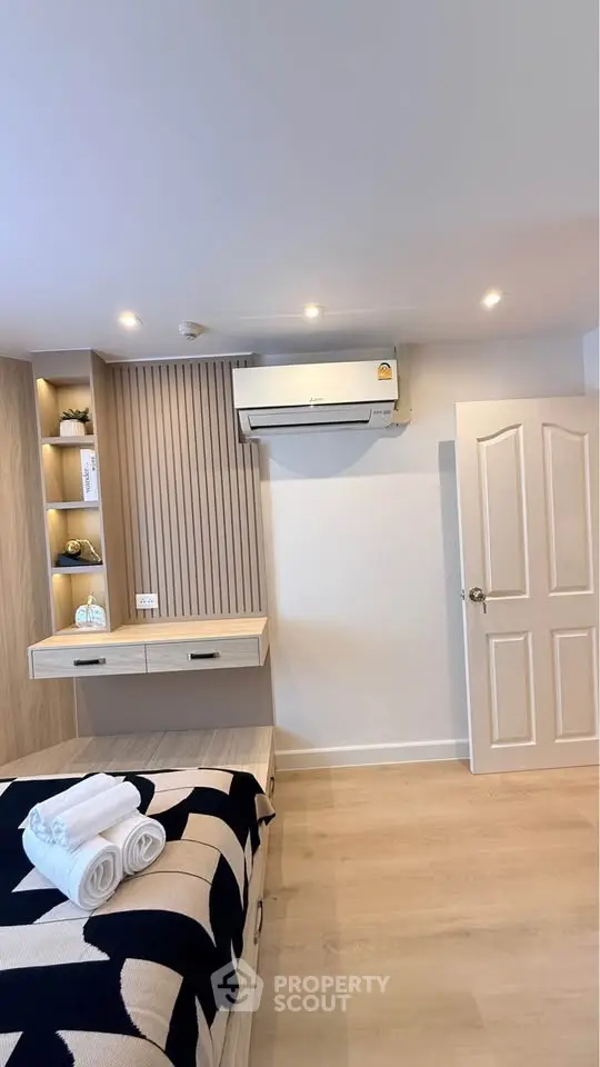 Modern bedroom with stylish decor and air conditioning, featuring a cozy bed and elegant wooden accents.