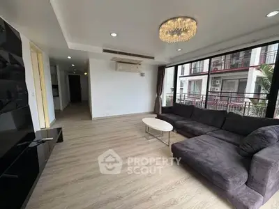 Spacious living room with modern chandelier and large sectional sofa in a bright apartment.